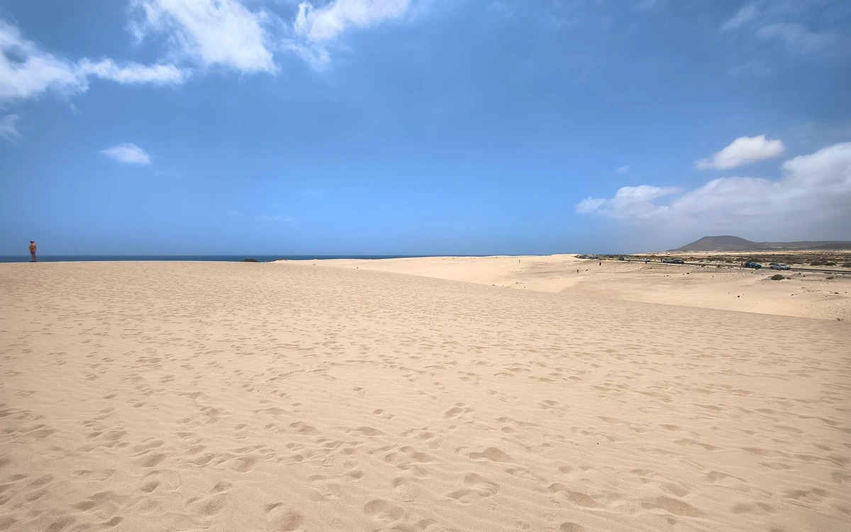 Helle Sandflächen und niedrige Dünen unter blauem Himmel bei Corralejo