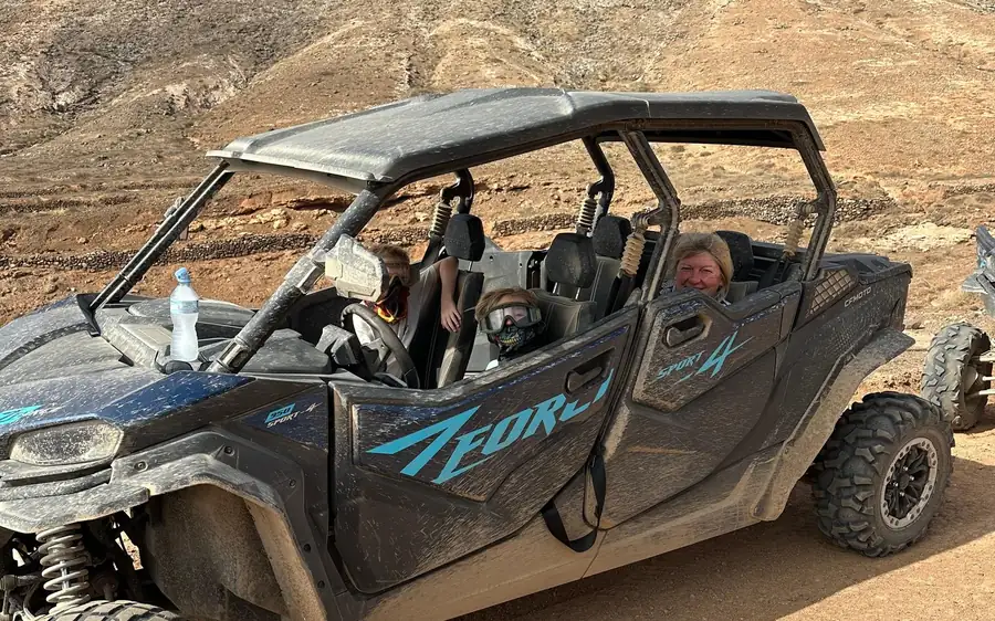 Ein viersitziger Buggy mit einer Familie an Bord auf staubiger Piste