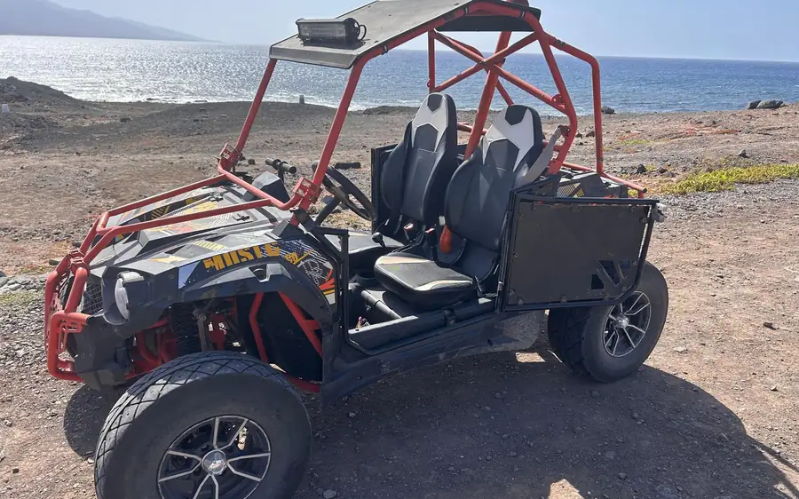 Ein zweisitziger Buggy mit rotem Rahmen über einer felsigen Küste und dem Meer